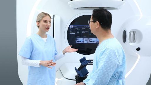 Female healthcare worker speaking to a male patient while he sits in front of the Elekta Harmony